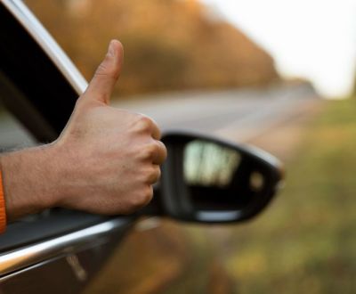 man-giving-thumbs-up-out-his-car-while-road-trip.jpg